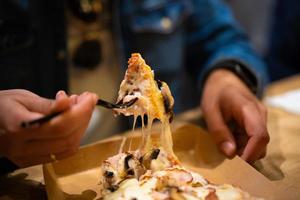 ein Stück Pizza mit geschmolzenem Käse, das sich ausdehnt foto
