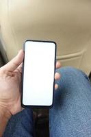 Hand, die ein Smartphone mit leerem Bildschirm in einem Auto hält foto