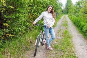 junge frau, die fahrrad im sommerstadtpark draußen fährt. aktive Menschen. Hipster-Mädchen entspannen und Fahrrad fahren foto