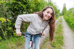 junge frau, die fahrrad im sommerstadtpark draußen fährt. aktive Menschen. Hipster-Mädchen entspannen und Fahrrad fahren foto