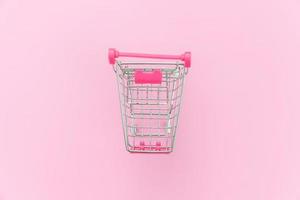 kleiner Supermarkt-Lebensmittel-Schubwagen zum Einkaufen von Spielzeug mit Rädern isoliert auf pinkfarbenem, pastellfarbenem, trendigem Hintergrund. verkauf kaufen einkaufszentrum markt shop verbraucherkonzept. Platz kopieren. foto