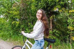 junge frau, die fahrrad im sommerstadtpark draußen fährt. aktive Menschen. Hipster-Mädchen entspannen und Fahrrad fahren foto