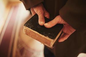 ein Buch in den Händen eines alten Mannes. kleine Bibel foto