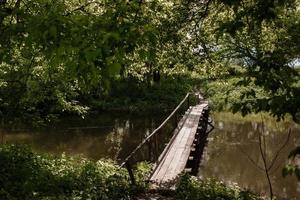 alte Holzbrücke, Holzbrücke über einen kleinen Fluss, Brücke mit der Natur. foto