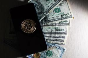 konzept mit geld, us-dollar, bitcoin und handy foto