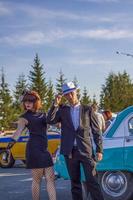 2022-08-12 Tatarstan, Bezirk Werchneuslonski, Dorf Savino. Erholungsort Swiyazhsky Hills. Kasaner Festival historischer Autos. Ein Mann und eine Frau in Retro-Kleidung posieren in der Nähe von Autos. foto