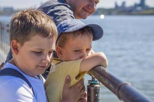 Kinder und ein Mann stehen und schauen über das Brückengeländer auf den Fluss foto