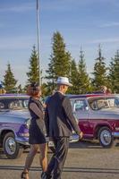 2022-08-12 Tatarstan, Bezirk Werchneuslonski, Dorf Savino. Erholungsort Swiyazhsky Hills. Kasaner Festival historischer Autos. Ein Mann und eine Frau in Retro-Kleidung posieren in der Nähe von Autos. foto