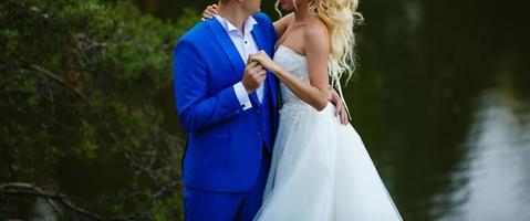 Ein junges Brautpaar in Hochzeitskleidern steht am Felsen am Meer foto