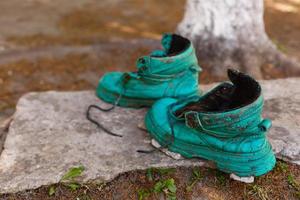 alter Schuh mit Moos in einem Frühlingswald bedeckt. abstraktes Bild. alte grüne Schuhe foto