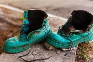 alter Schuh mit Moos in einem Frühlingswald bedeckt. abstraktes Bild. alte grüne Schuhe foto