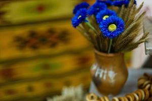 Vase mit Weizenähren auf Kokosnuss- und Holzhintergrund Ohren in einer Tonvase, blaue Blumen, Bagels foto