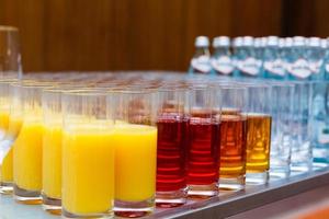 Lebensmittelhintergrund. Viele Gläser mit natürlichem Saft mit Orange am Buffettisch foto