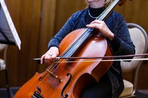 Ein junges Mädchen spielt im Dunkeln Cello. Hände aufs Cello foto