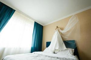 das Zimmer der Braut mit Hochzeitskleid und Bett foto