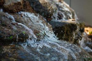 Nahaufnahme von Wasser, das von einem Wasserfall auf Felsen spritzt foto