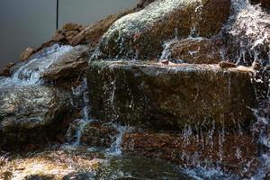 Nahaufnahme von Wasser, das von einem Wasserfall auf Felsen spritzt foto