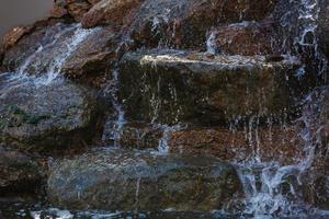 Nahaufnahme von Wasser, das von einem Wasserfall auf Felsen spritzt foto