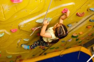 kleines Mädchen, das in der Kletterhalle im Freien aufsteigt foto