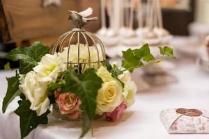 Vogelkäfig mit rosa Blumen im Inneren auf rustikalem Holzhintergrund. Platz kopieren. foto