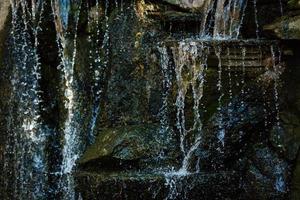 Nahaufnahme von Wasser, das auf Felsen von einem Wasserfall spritzt Wasser auf dekorativen Steinen foto