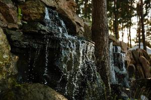 Nahaufnahme von Wasser, das auf Felsen von einem Wasserfall spritzt Wasser auf dekorativen Steinen foto