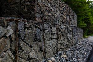 Böschungs- und Erdstützmauermanagement mit Felsen und Maschendrahtkäfigsystem in tropischem hügeligem Gelände foto