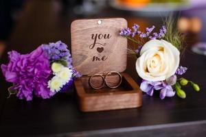 Hochzeit Ansteckblume. Goldringe lagen in einer Holzkiste. lila weiße zusammensetzung. foto