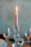 Rosa Kerze in einem Kandelaber auf einem Tisch, Nahaufnahme mit Gläsern Wein und Champagner