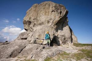 Natur erkunden. Junge trägt Rucksack beim Wandern in der Nähe von großen Steinen im Hügel. pidkamin, ukraine. foto