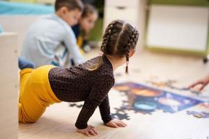 Kinder verbinden Puzzleteile in einem Kinderzimmer im Erdgeschoss zu Hause. lustige familienaktivität freizeit. foto