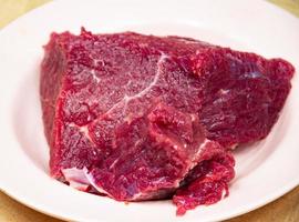 große Stücke frisches rotes Rindfleisch auf einem weißen Teller. Schlachthof. Metzgerei. Schweinefleisch. foto