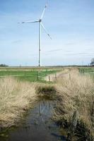 Windkraftanlage auf einem Feld, das durch einen mit Wasser gefüllten Graben geteilt wird, auf dem Land. sauberes Energiekonzept. foto