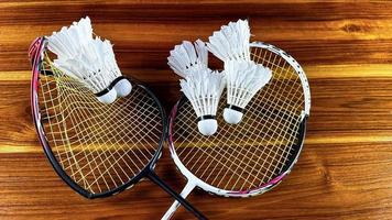 Nahaufnahme von kaputten Badmintonschlägern und weißen Badminton-Shuttle-Hähnen auf braunem Holzhintergrund foto