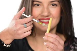 schöne Frau spritzt Cholesterin in die Seite des Hamburger-Sandwiches foto