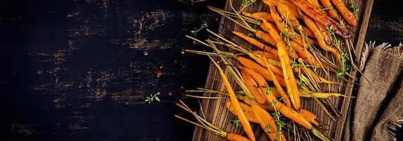 gebackene Bio-Karotten mit Thymian, Honig und Zitrone. Bio veganes Essen. Banner. Ansicht von oben foto