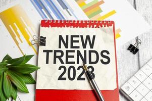 Trends 2023 Text auf Papier mit rotem Notizbuch und Stift, Taschenrechner und Diagrammen foto