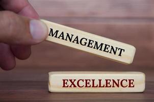 Hand, die Management-Excellence-Text auf Holzklötzen hält. Management-Exzellenz und Geschäftskonzept foto