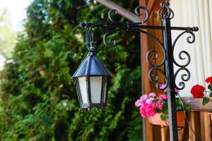 Alte verrostete Laterne auf einem Holzhaus und Blumen foto