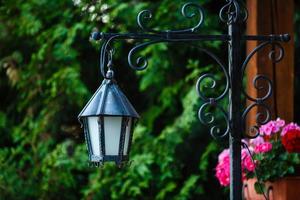 Alte verrostete Laterne auf einem Holzhaus und Blumen foto