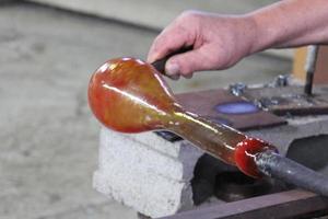 Der Meister arbeitet mit Glas in einer Glasfabrik. foto