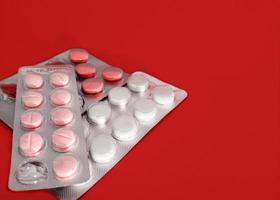 pharmazeutische Zubereitung. Öffnen Sie Blister mit Tabletten auf rotem Hintergrund. Medizin. foto