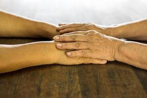 Nahaufnahme Seitenansicht, faltige Hände einer älteren thailändischen Frau, die sich zum Trost halten. foto