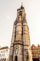 hoher mittelalterlicher glockenturm, der sich über der straße mit alten europäischen häusern erhebt, tournai, wallonische gemeinde, belgien foto