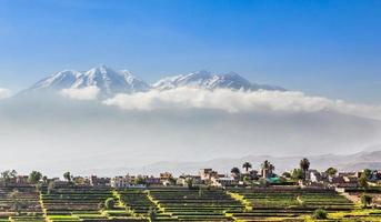 Schneekaps des Chachani-Vulkans über den Feldern und Häusern der peruanischen Stadt Arequipa, Peru foto