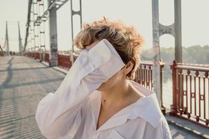 Nahaufnahme einer Frau, die das Gesicht hinter dem Hemdärmel versteckt und auf einem Porträtbild der Brücke steht foto