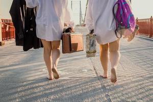 Nahaufnahme barfüßiger Frauen mit Koffern, die über das Brückenkonzeptfoto gehen foto