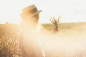 Nahaufnahme Mädchen in Strohhut mit Blumenstrauß, umgeben von Sonnenlicht Blendung Konzeptfoto foto