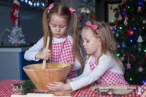 süße kleine mädchen, die lebkuchenplätzchen für weihnachten zubereiten foto