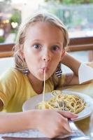 entzückendes kleines Mädchen, das Spaghetti im Restaurant im Freien isst foto